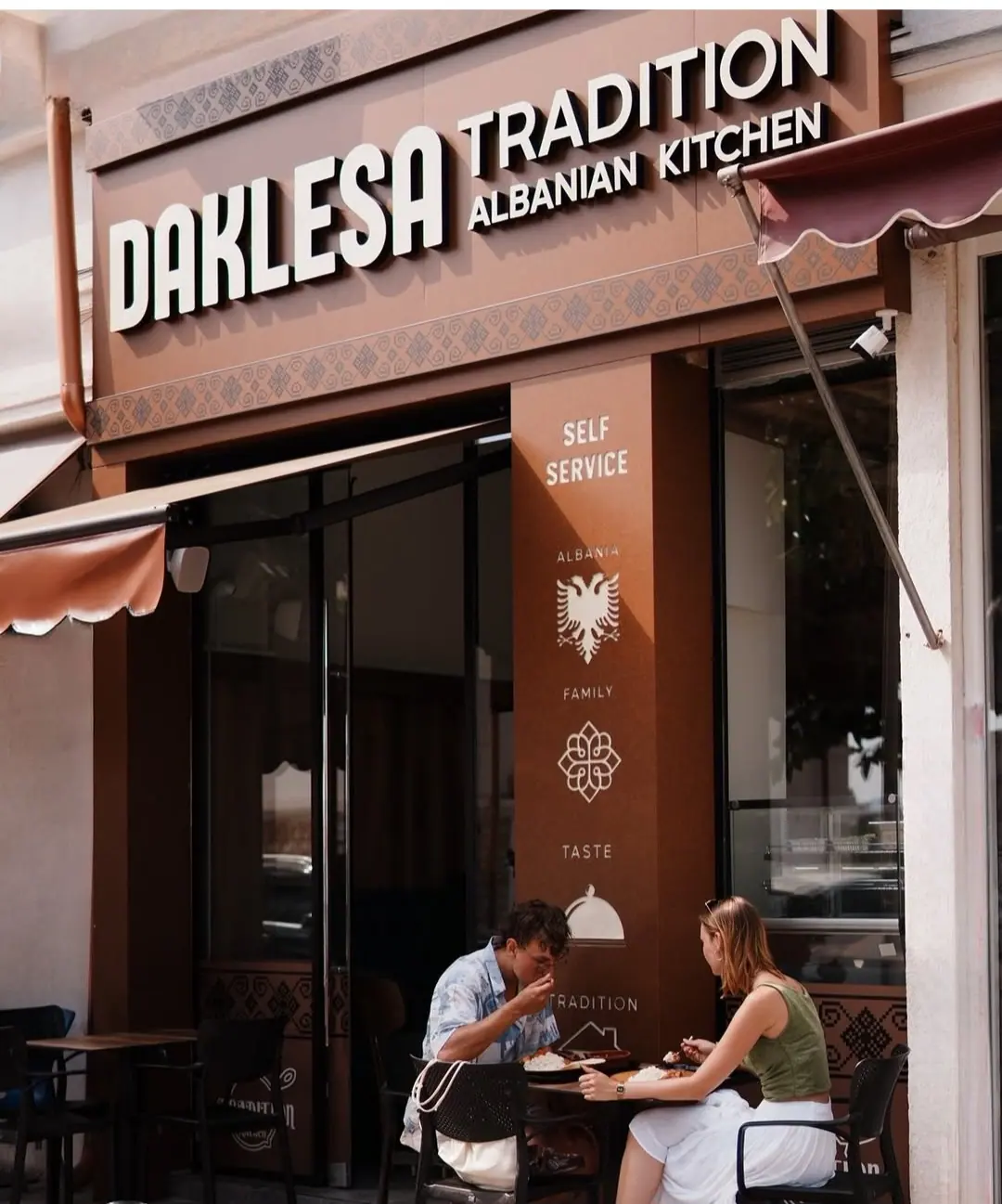 Guests eating outside the Daklesa Tradition storefront in Sarandë